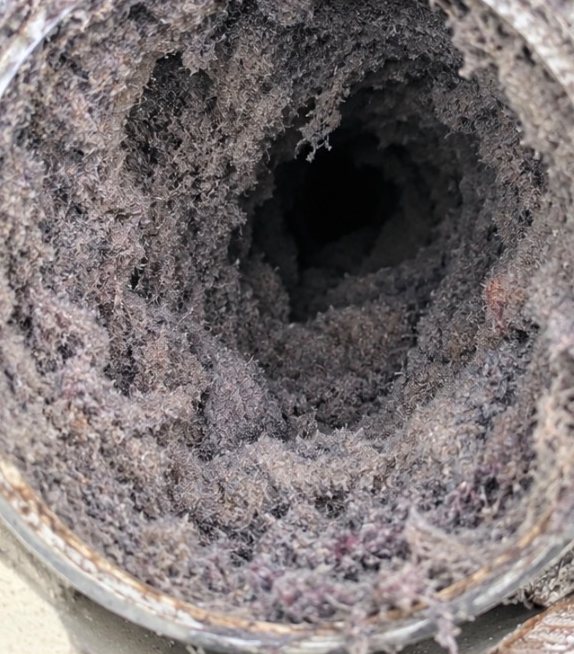Before: a dryer vent duct packed with grey lint, leaving only a small opening for air